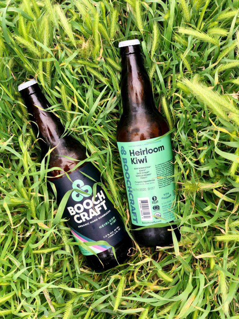 two bottles of beer sitting on top of a lush green field.