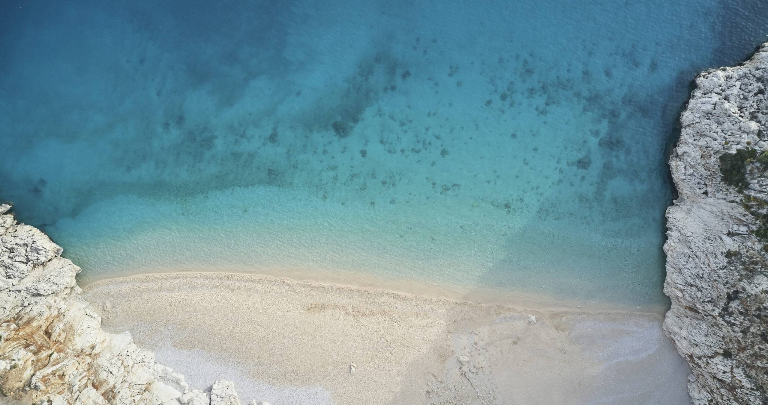 an aerial view of a sandy beach and blue water.