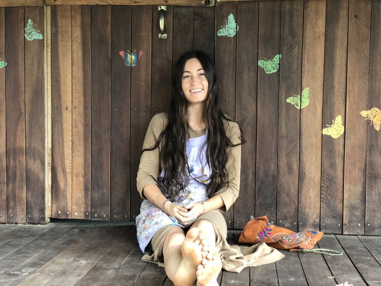 a woman sitting on a wooden floor next to a wall.
