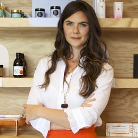 a woman standing in front of a shelf of cosmetics.