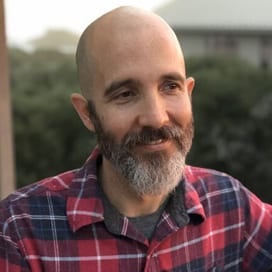 a man with a bald head wearing a plaid shirt.