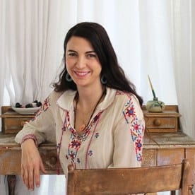 a woman sitting at a wooden table smiling.