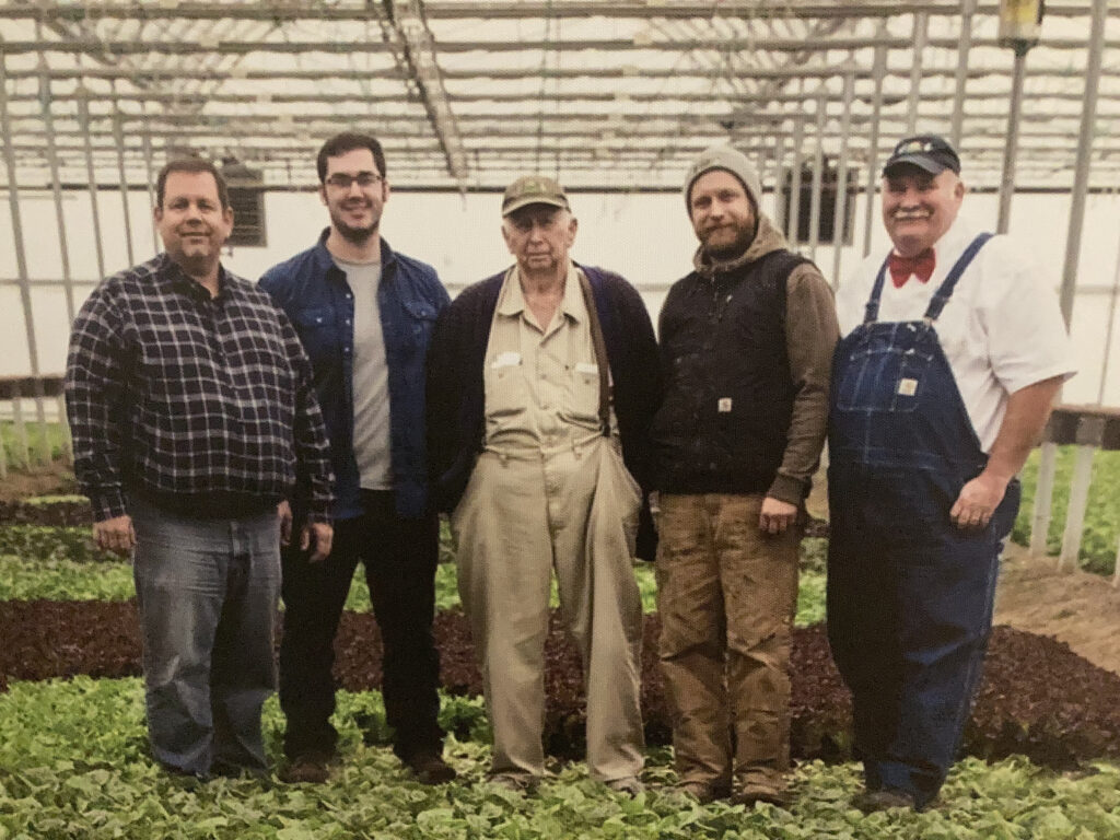 a group of men standing next to each other in a greenhouse.