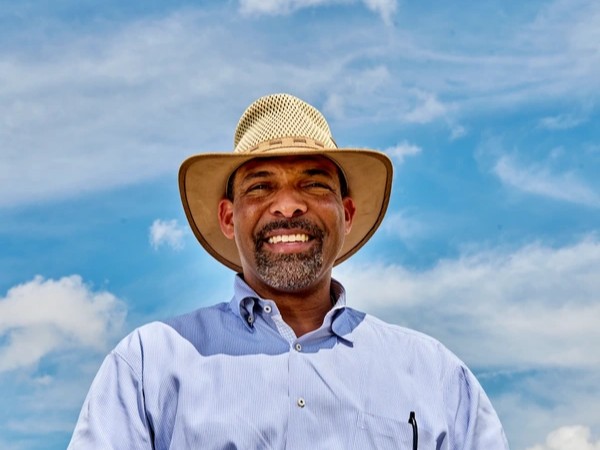 Smiling farmer in a straw hat against a bright blue sky